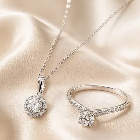 Dây chuyền và nhẫn bạc tinh tế của Queen's Silver trên nền lụa champagne